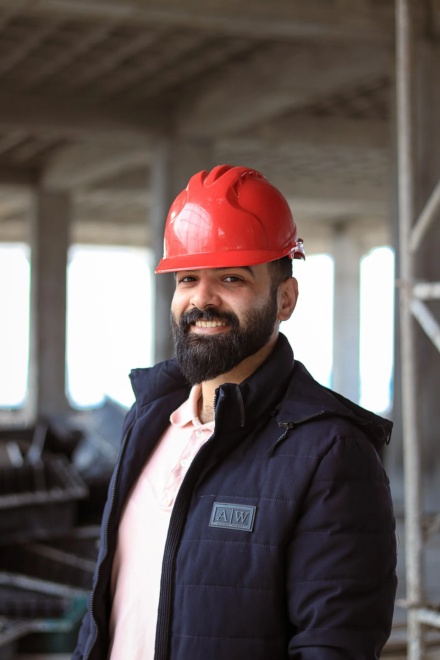 A contractor in a red hard hat smiling on site.