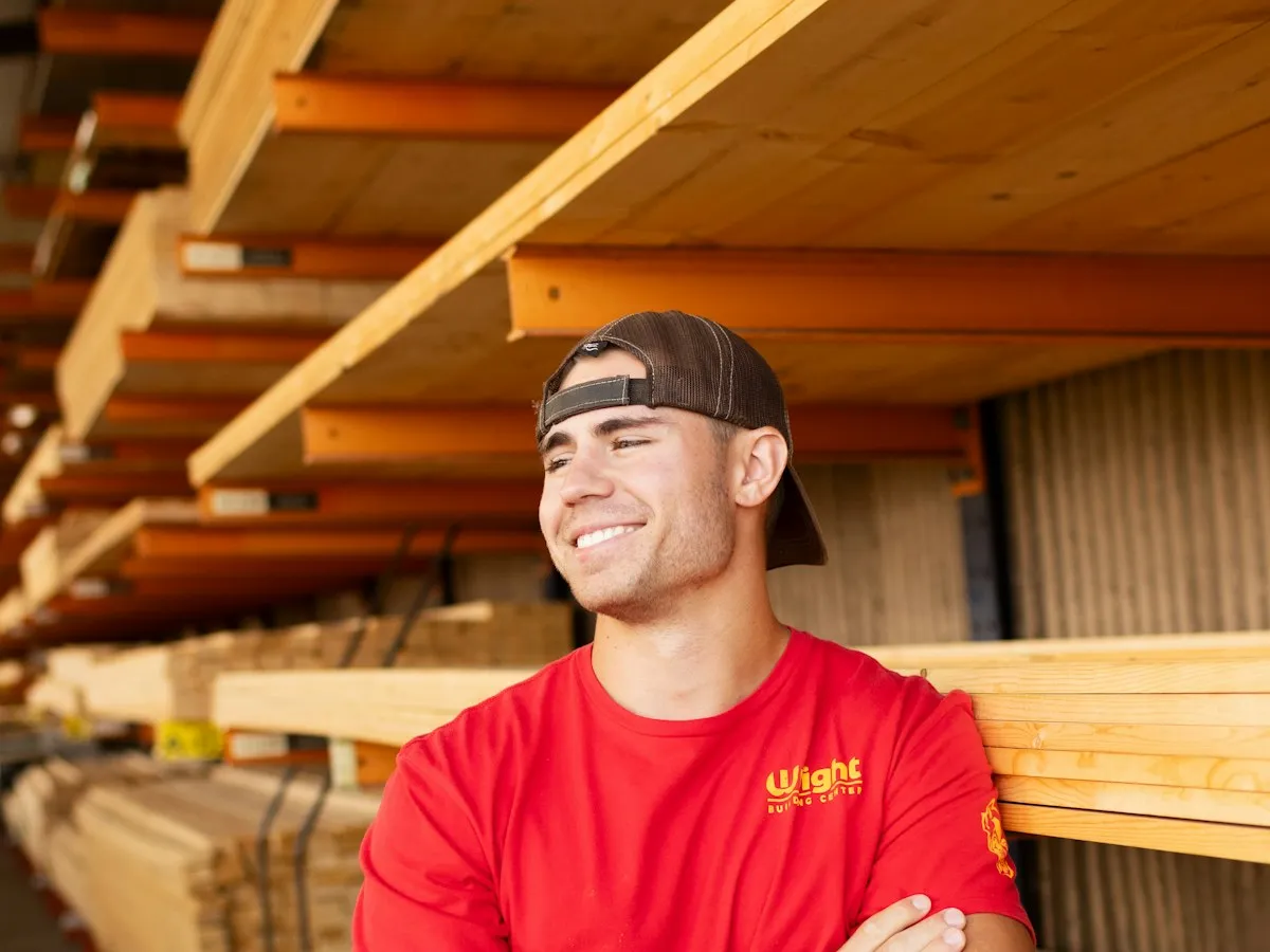 A business owner smiling in his lumber yard.